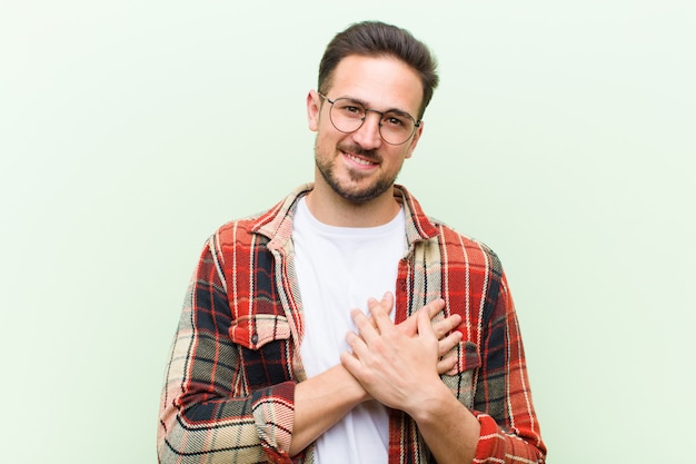 sentindo-se romântico, feliz e apaixonado, sorrindo alegremente e segurando as mãos perto do coração