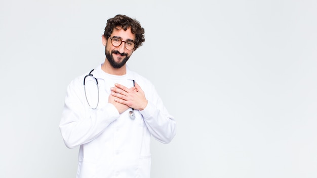 sentindo-se romântico, feliz e apaixonado, sorrindo alegremente e segurando as mãos perto do coração