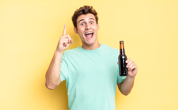 Sentindo-se um gênio feliz e animado após realizar uma ideia, levantando o dedo alegremente, eureka !. conceito de garrafa de cerveja