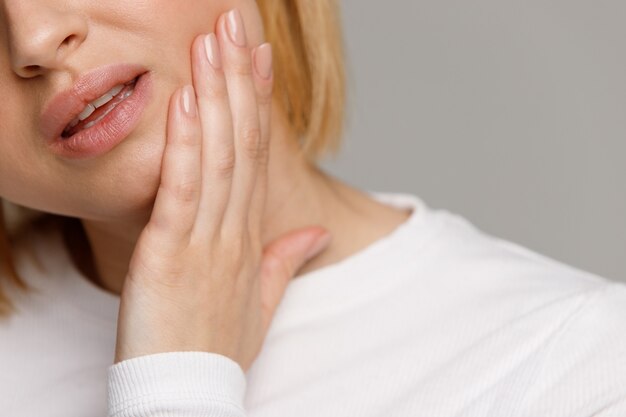 Sentir dor feminina, segurando sua bochecha com a mão, sofrendo de dor de dente ruim