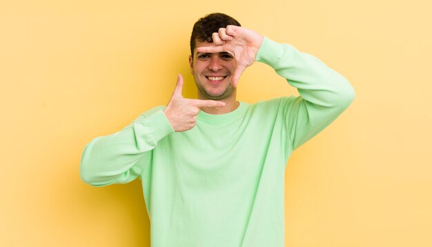 Sentir-se feliz, amigável e positivo, sorrindo e fazendo um retrato ou moldura com as mãos