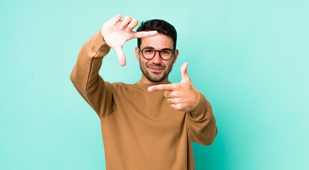 Sentir-se feliz, amigável e positivo, sorrindo e fazendo um retrato ou moldura com as mãos