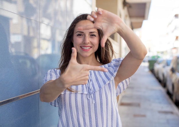 Sentir-se feliz, amigável e positivo, sorrindo e fazendo um retrato ou moldura com as mãos