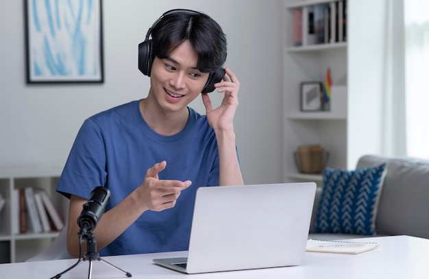 Sentirse bien, feliz y positivo en el trabajo Joven empresario asiático con auriculares en una videollamada con clientes en una computadora portátil