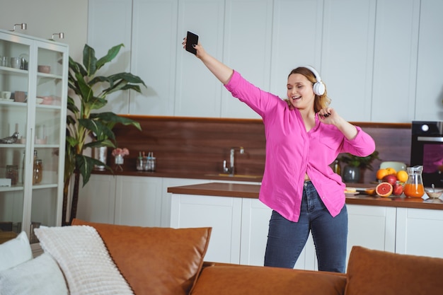 Sentirse bien. Modelo alegre usando audífonos, teniendo actividades matutinas en casa