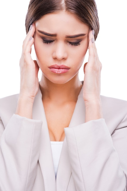 Sentirse cansado. Joven empresaria deprimida tocándose la cara y manteniendo los ojos cerrados mientras está de pie contra el fondo blanco.