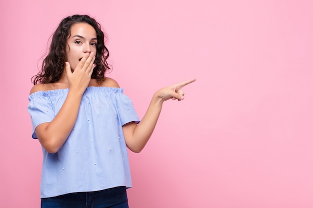 sentirse feliz, conmocionado y sorprendido, cubriéndose la boca con la mano y señalando el espacio de copia lateral