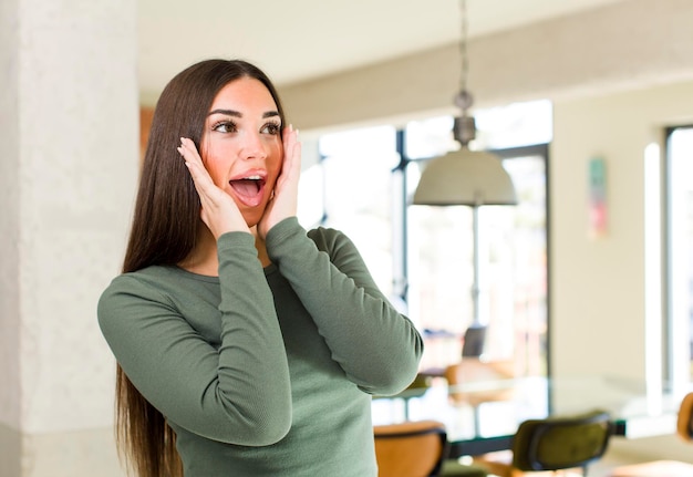 Foto sentirse feliz emocionado y sorprendido mirando hacia un lado con ambas manos en la cara