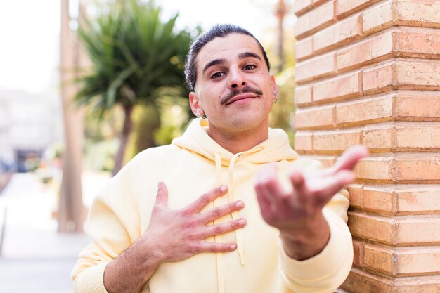 Foto sentirse feliz y enamorado sonriendo con una mano al lado del corazón y la otra estirada al frente