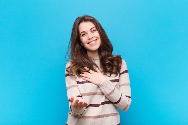 sentirse feliz y enamorado, sonriendo con una mano al lado del corazón y la otra estirada al frente