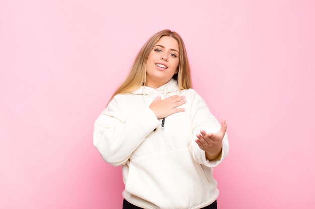 sentirse feliz y enamorado, sonriendo con una mano al lado del corazón y la otra estirada al frente