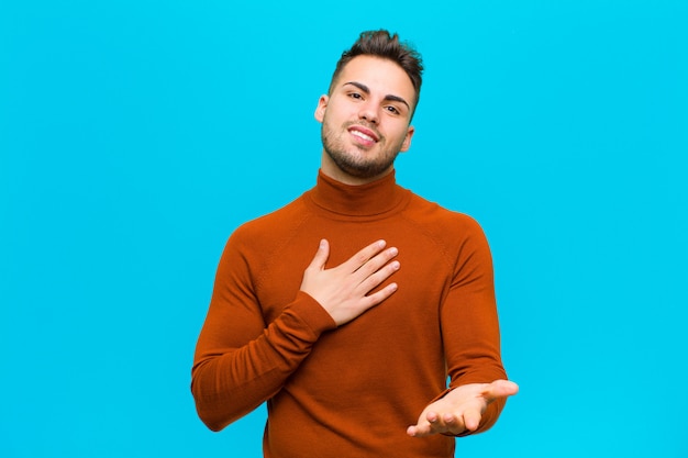 sentirse feliz y enamorado, sonriendo con una mano al lado del corazón y la otra estirada al frente