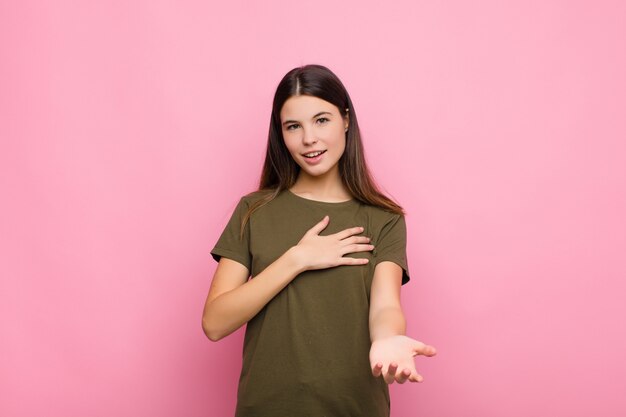 sentirse feliz y enamorado, sonriendo con una mano al lado del corazón y la otra estirada al frente