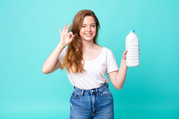 Sentirse feliz, mostrando aprobación con un gesto aceptable y sosteniendo una botella de leche.