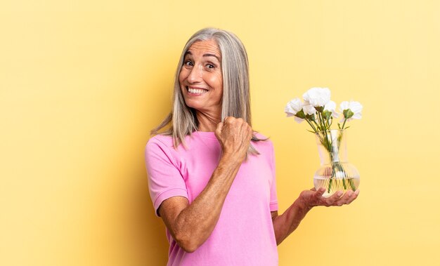 Sentirse feliz, positivo y exitoso, motivado al enfrentar un desafío o celebrar buenos resultados sosteniendo flores decorativas