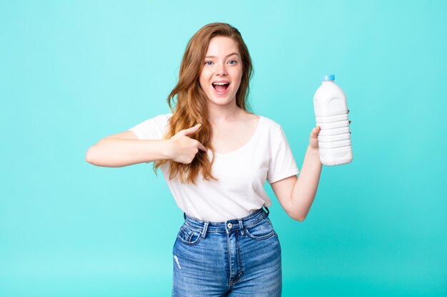 Sentirse feliz y señalando a sí mismo con un emocionado y sosteniendo una botella de leche