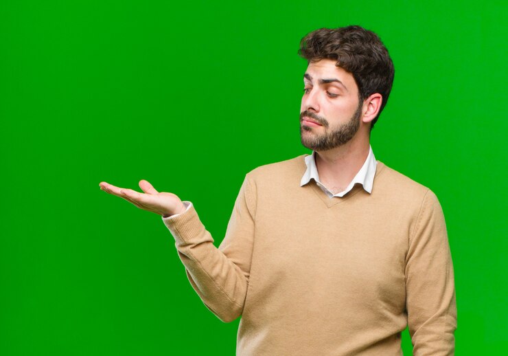 Foto sentirse feliz y sonreír casualmente, mirar un objeto o concepto sostenido en la mano al costado