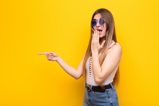 sentirse feliz, sorprendido y sorprendido, cubriéndose la boca con la mano y señalando el espacio de copia lateral