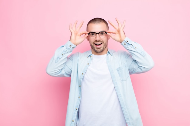 sentirse sorprendido, asombrado y sorprendido, sosteniendo gafas con una mirada asombrada e incrédula