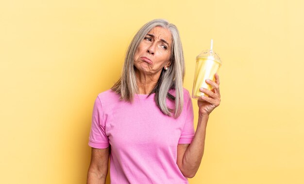 Sentirse triste y quejumbroso con una mirada infeliz, llorar con una actitud negativa y frustrada y sosteniendo un batido.