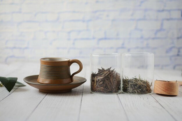 Foto seque las hojas de té en un tarro y una taza de té en la mesa