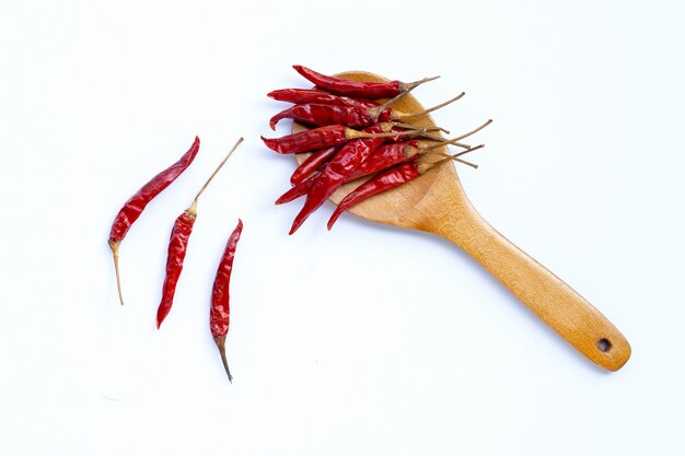 Seque las pimientas de chile candentes en la cuchara de madera en el fondo blanco. Copia espacio