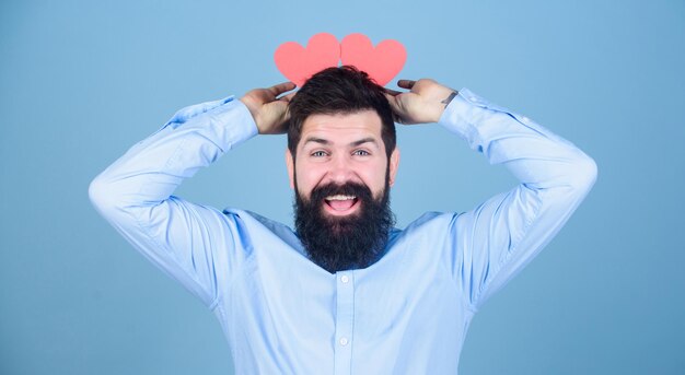 Ser de cabeça cura Hipster com pequenos corações Homem barbudo segurando corações vermelhos na cabeça Homem sexy dos namorados com cartões em forma de coração Feliz dia dos namorados expressando seu amor