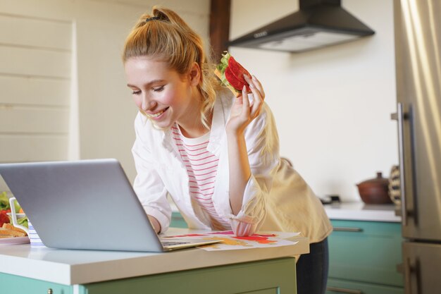 Ser feliz. Mujer complacida manteniendo una sonrisa en su rostro mientras almuerza durante su trabajo