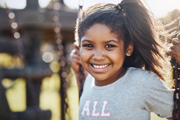 Ser jovem significa ter dias de diversão Retrato de uma adorável garotinha brincando em um balanço no parque