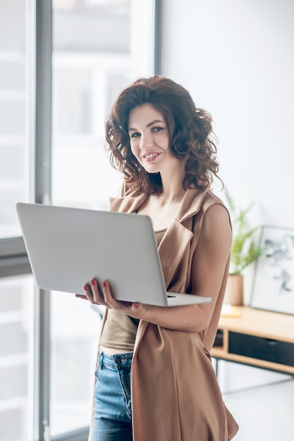 Ser productivo. Mujer bonita de pelo oscuro trabajando en un portátil y mirando contento