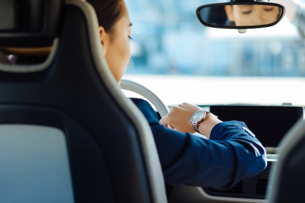 Ser puntual. Mujer atractiva agradable mirando su reloj mientras intenta no llegar tarde