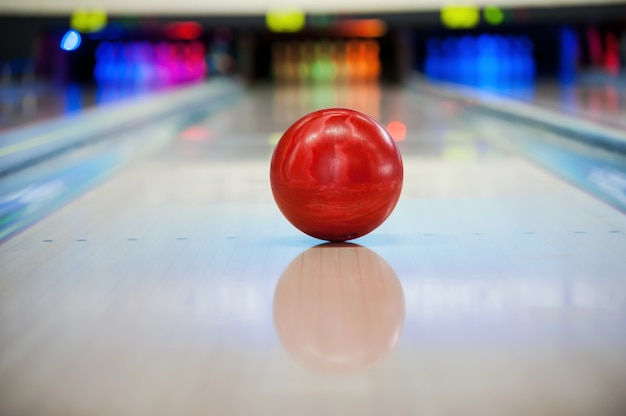 ¡Será huelga! Close-up de bola de bolos de color rojo brillante rodando a lo largo de la bolera