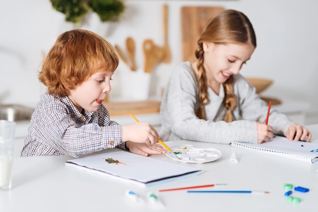 Esto será legendario. Niños encantadores, apasionados y animados que se divierten pintando cosas con acuarelas mientras pasan el fin de semana juntos