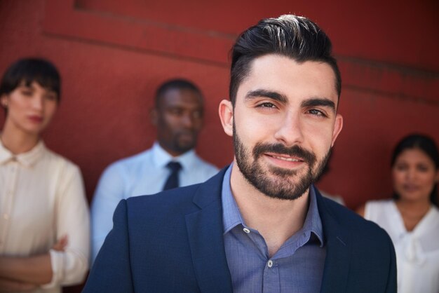 Foto será mejor que veas cómo alcanzamos la grandeza retrato de un joven hombre de negocios parado afuera con sus colegas en el fondo