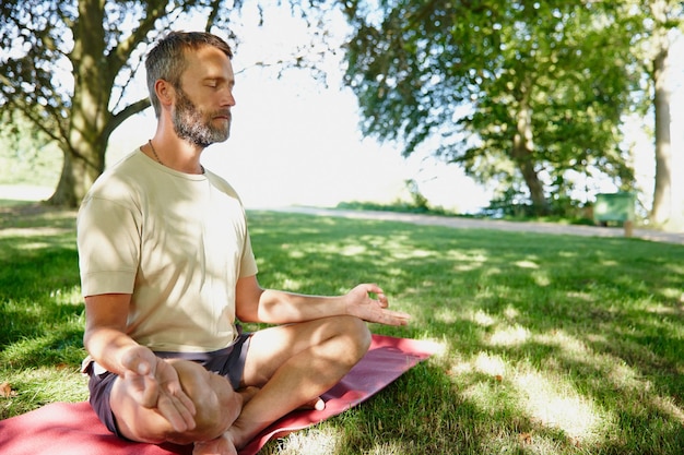 Serene debaixo das árvores Foto de um homem maduro bonito meditando na posição de lótus ao ar livre