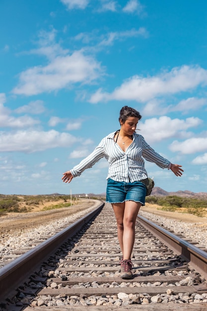 Foto serenidad ferroviaria mujer abrazando la brisa del desierto en las vías del tren