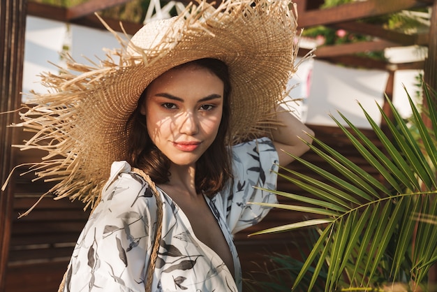 séria incrível jovem bonita na praia andando em uma bela manhã ensolarada sobre plantas tropicais.