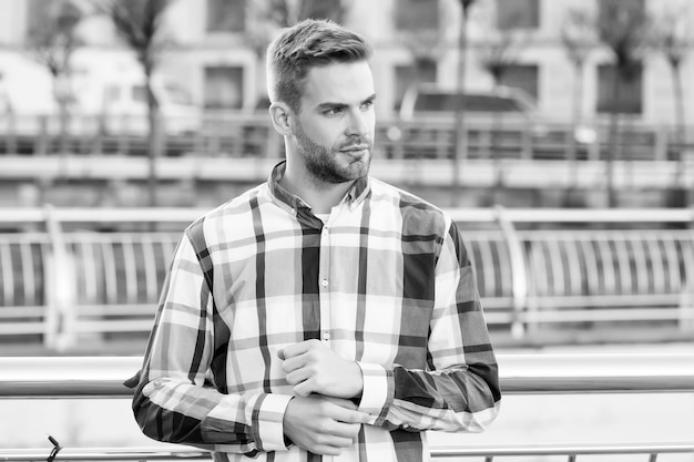 Seriamente guapo Hombre guapo de pie al aire libre urbano Aspecto atractivo de un chico joven Aseo masculino Peluquería Peluquería Tendencia de la moda Estilo casual Ropa de calle y ropa de hombre