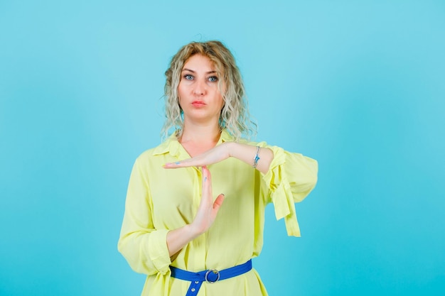 Seriamente mujer rubia está mostrando y gestos sobre fondo azul.