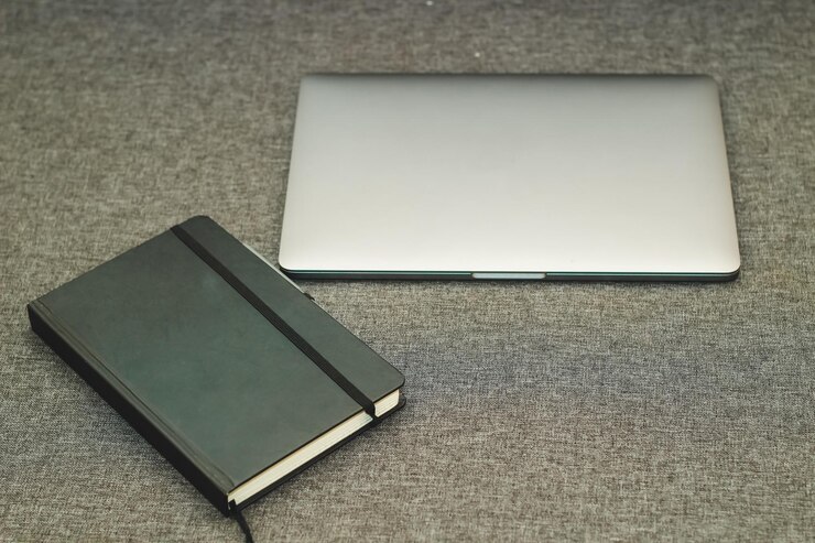Foto serie de portátiles de metal plano sobre la mesa con un diario de negocios