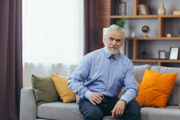 Serio para el abuelo pensativo sentado en el sofá en casa