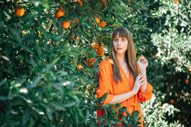 En serio, una joven vestida de naranja está mirando a la cámara en un jardín naranja