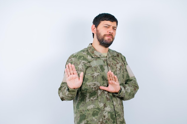Foto sério militar está hsowing gesto de parada com as mãos no fundo branco