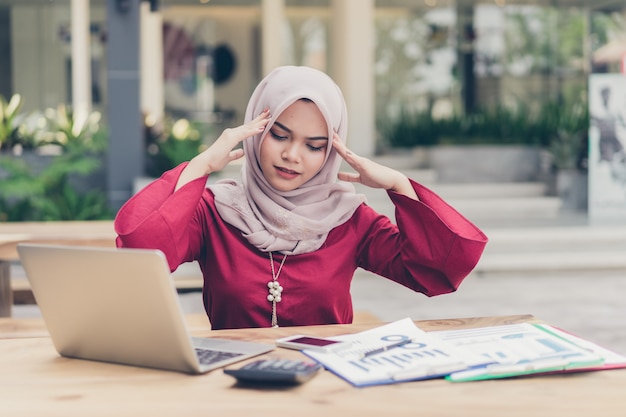 En serio, la mujer de negocios musulmana asiática tiene dolor de cabeza.