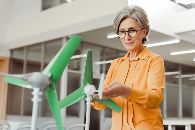 Seriöse leitende Ingenieurin, die einen elektrischen Windmühle-Generator hält, plant ein Innovation-Startup