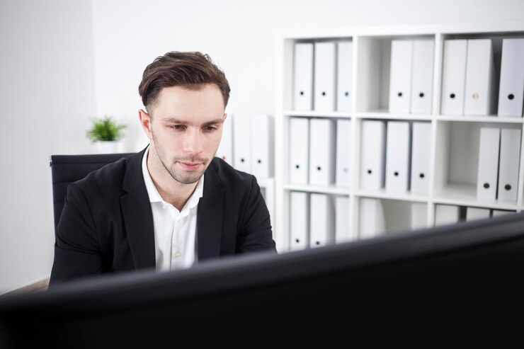 Seriöser Geschäftsmann blickt auf Computerbildschirm