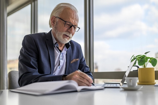 Seriöser Geschäftsmann schreibt Geschäftsplan per Laptop am Schreibtisch im Firmenbüro
