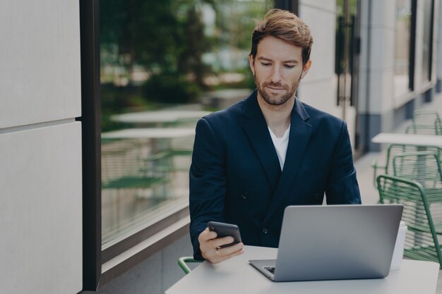 Seriöser männlicher Chef in eleganter Kleidung arbeitet online auf Laptop-Computern