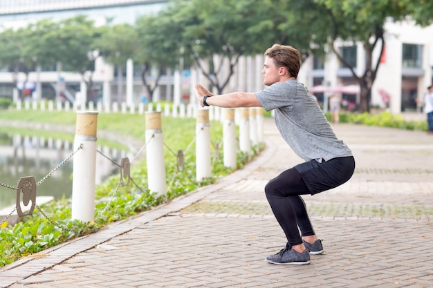 Serious Sporty Man Doing Squats im Freien