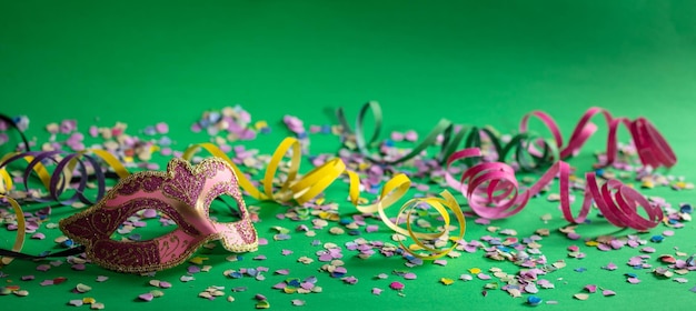 Serpentinas de máscara de carnaval y confeti sobre fondo verde brillante